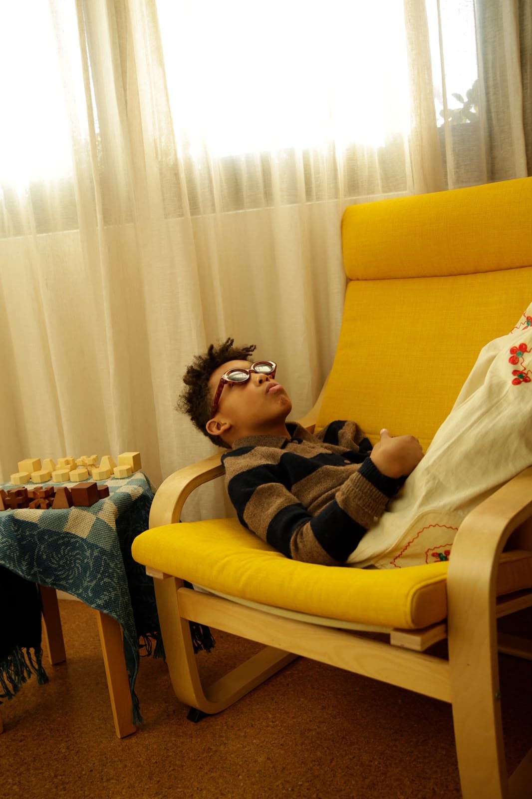 Arlo reclining in a yellow chair beside a wooden chess set